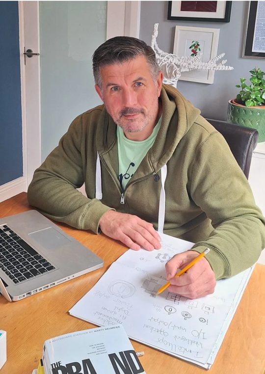 Barry O'Connor sketching logo ideas at his desk
