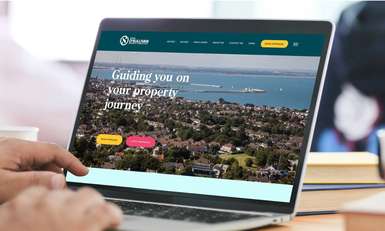 Laptop showing the John O'Sullivan website with an aerial view of Dún Laoghaire