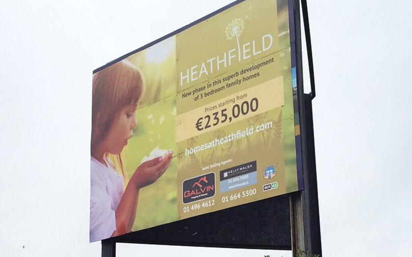 Heathfield billboard beside the road, with a girl blowing a dandelion and prices from €235,000
