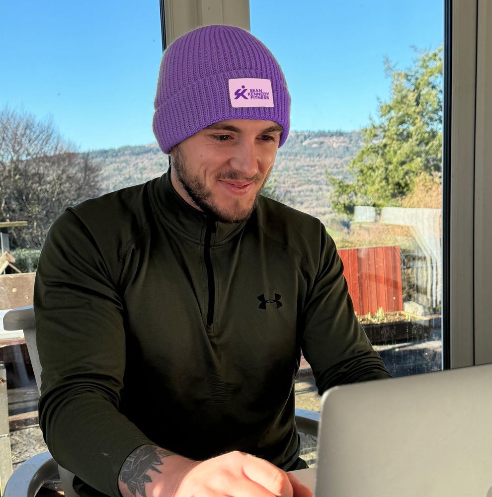 Sean Kennedy wearing a purple branded beanie, working at a laptop