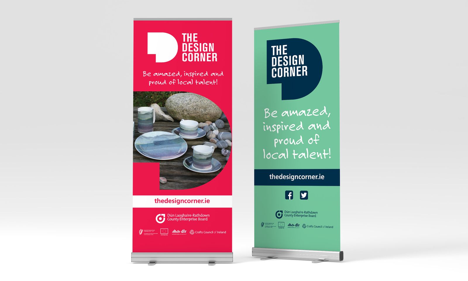 Two The Design Corner roll-up banners, one red and one green